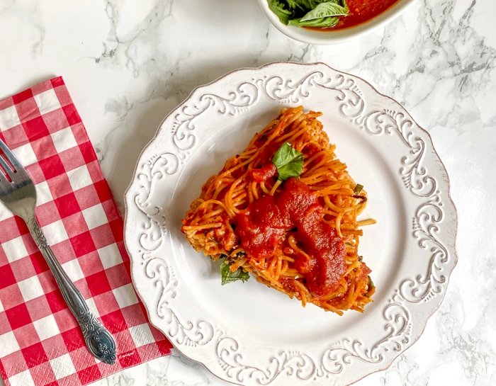 spaghetti pie on plate with sauce on top