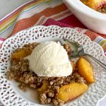 peach crisp on white plate with ice cream