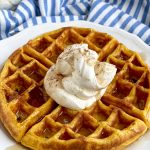 pumpkin waffle on plate with whipped cream and syrup