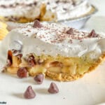 a slice of banana marshmallow pie on plate with whole pie in background.