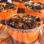 orange and black Halloween pudding cups with crushed cookies and sprinkles.